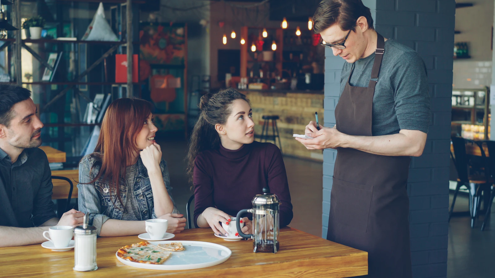 A waiter takes an order at a restaurant table