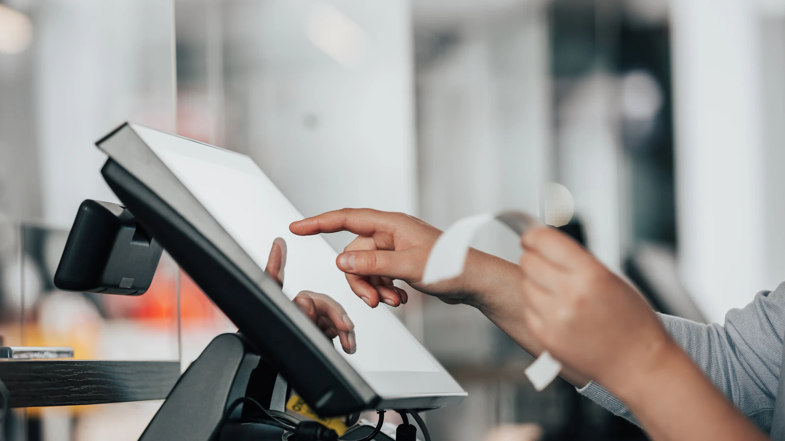 Person using a touchscreen POS while holding a receipt